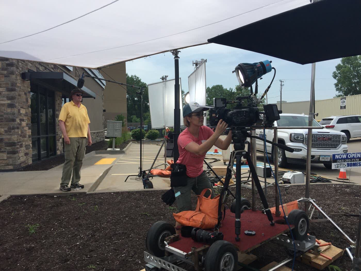 Camera operator on a dolly rig outside a storefront