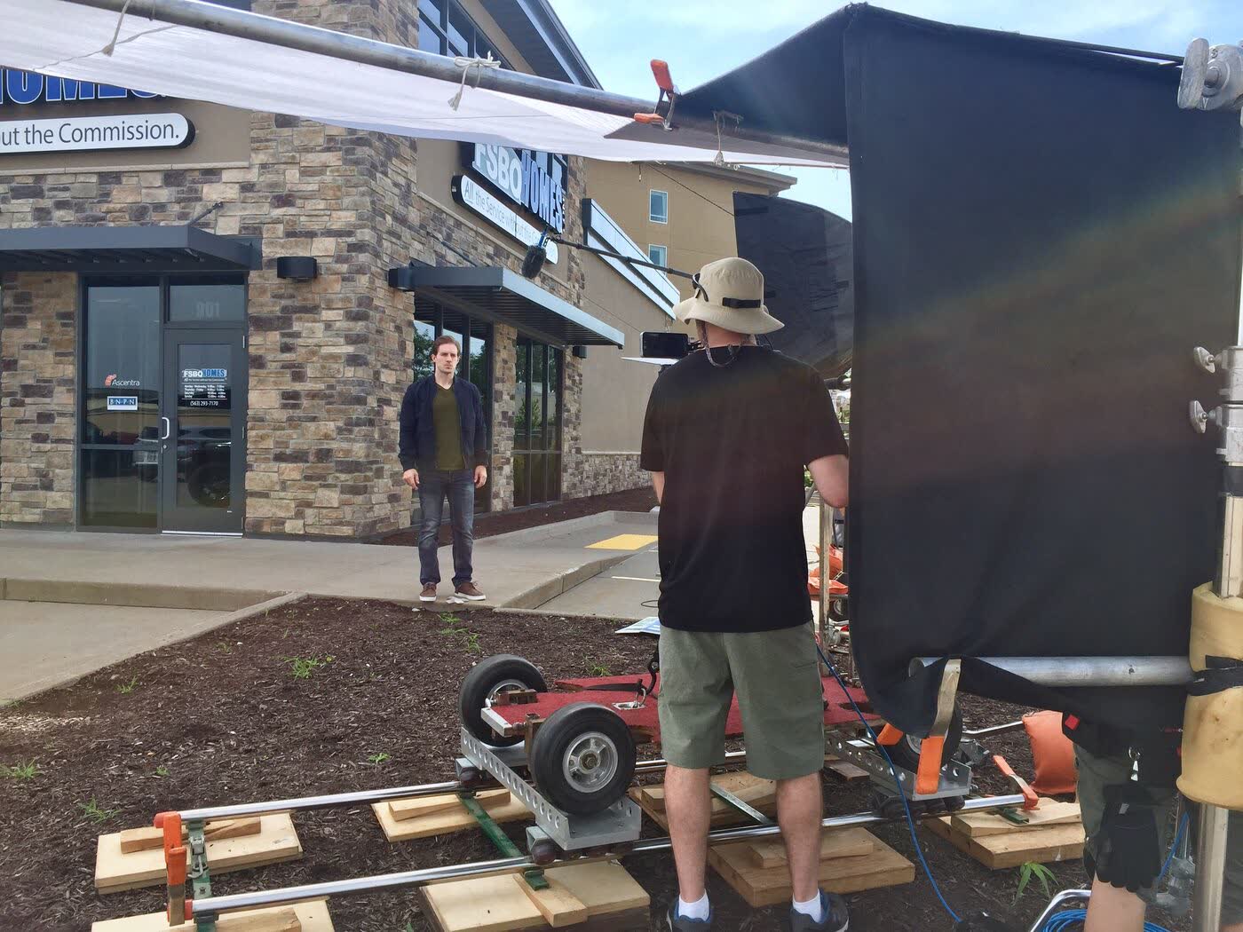 Camera operator on a dolly rig outside a storefront